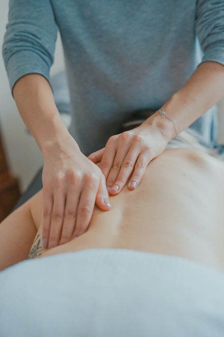 Person erhält Rückenmassage, Hände massieren unteren Rückenbereich